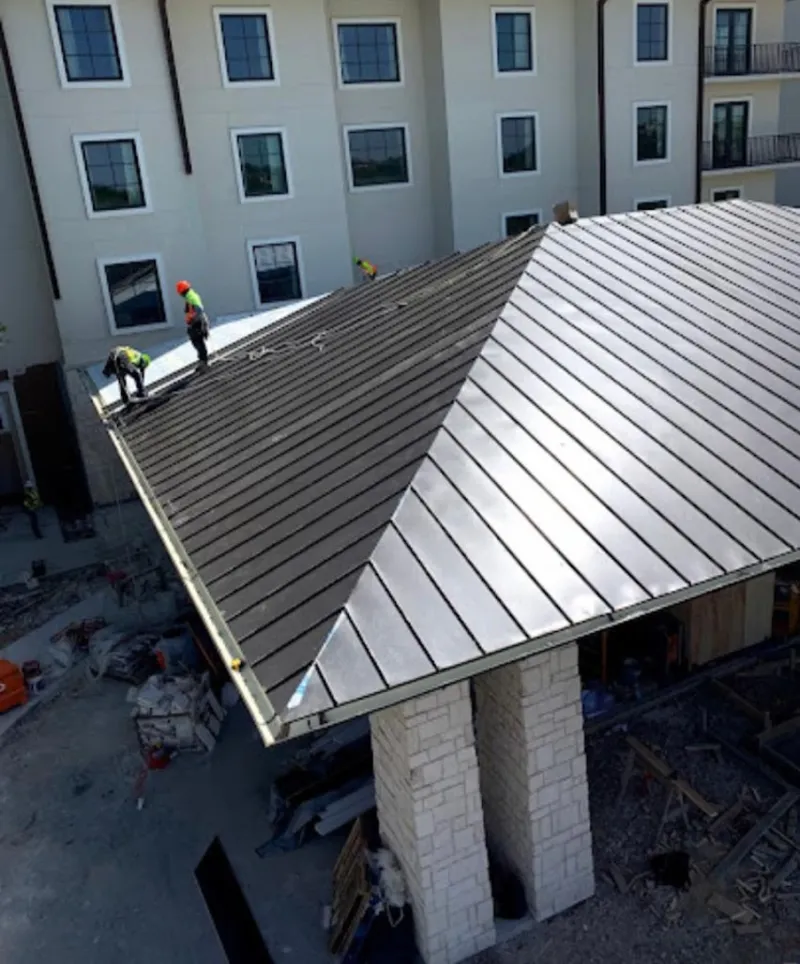 Crew installing standing seam metal roof panels on a commercial project in De Soto